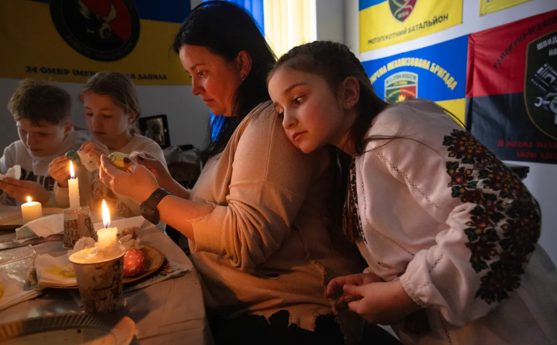 Жінка та дівчинка розписують писанки при свічках